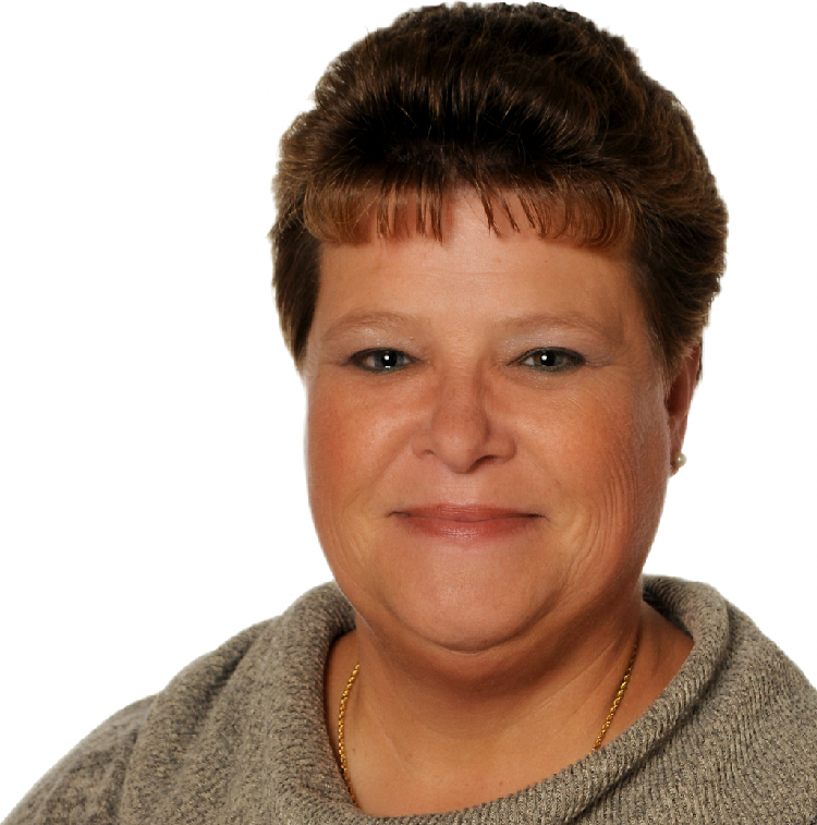 Close-up portrait of a smiling middle-aged woman with short brown hair, wearing a gray knit sweater and a gold necklace, against a white background.